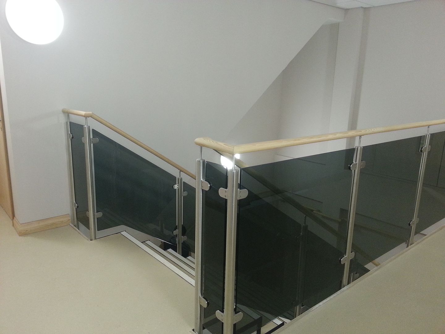 Glazed stainless steel balcony balustrade with coloured glass infills and ash timber handrail